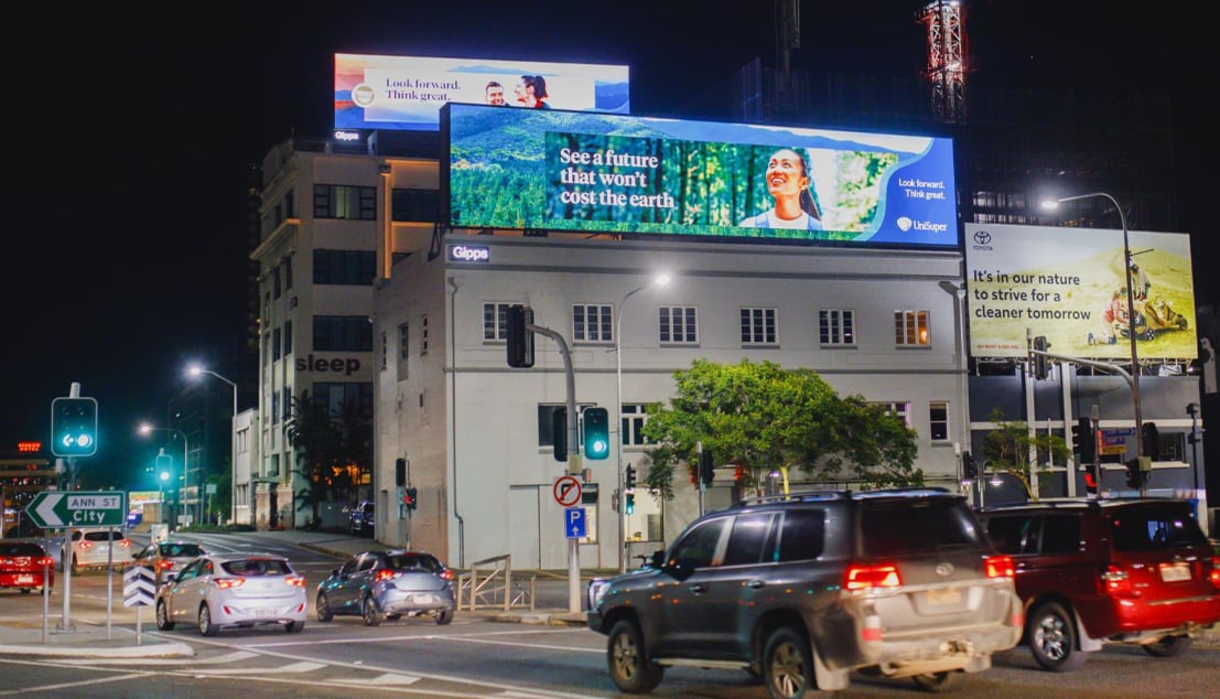 Campaign billboards are displayed at night on a busy street corner