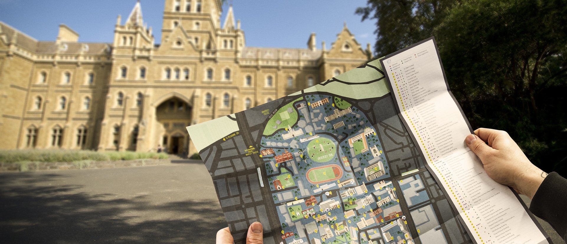 Tourist holds up a campus map outside a historic building.
